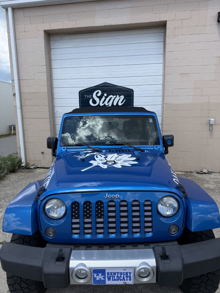 Blue Jeep Wrangler with Oak & Blue custom branding wrap parked outside the sign shop in Lexington, Kentucky.