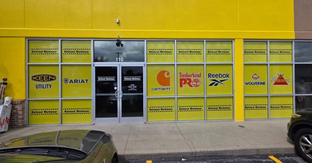Custom yellow window graphics featuring workwear brand logos and directional signage for National Workwear in Lexington, KY.